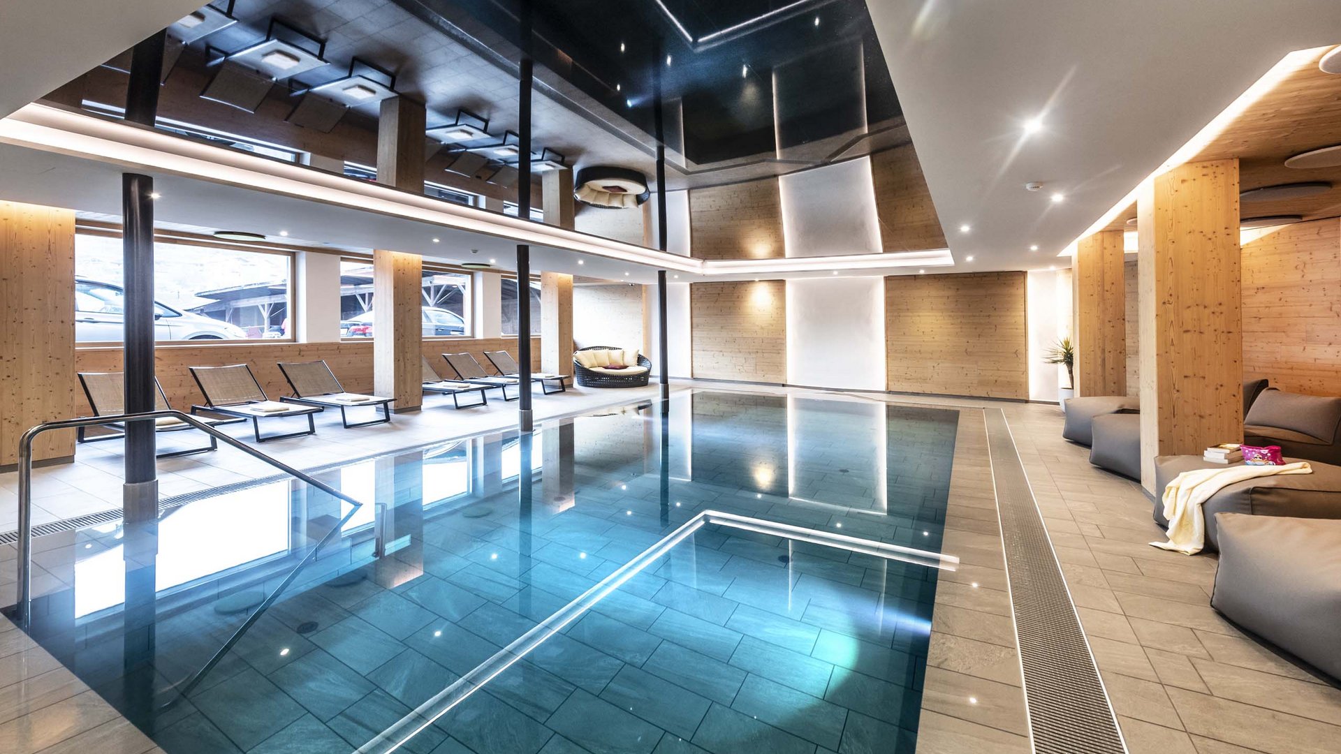 Relaxation at our hotel in Kastelruth with pool Modern indoor pool with wood paneling and lounge chairs
