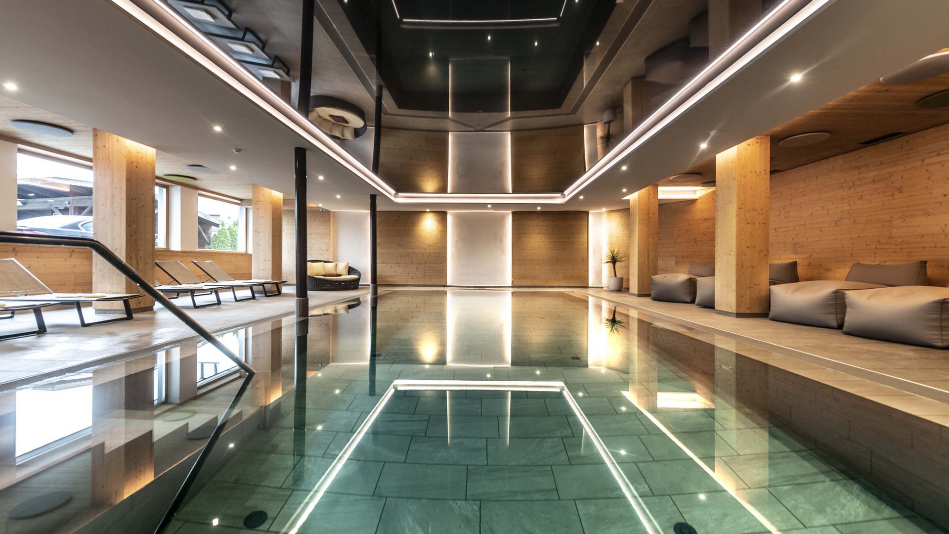 Flexibilität im Hotel in Kastelruth Moderner Innenpool mit Holzwänden und Liegen in einem Wellnessbereich